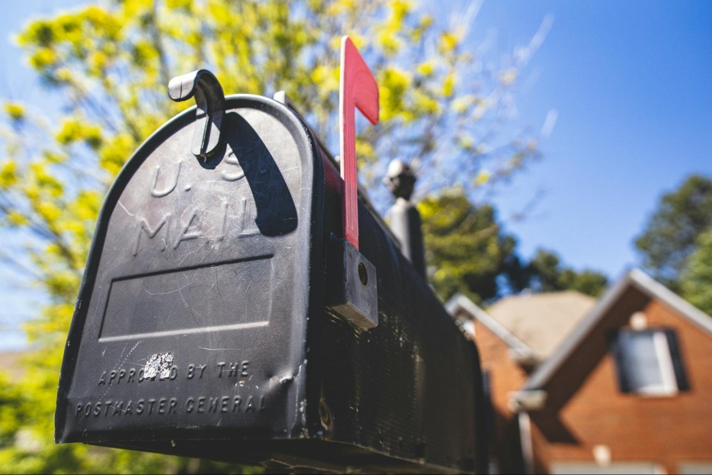 Black US Mailbox, Curbside, with red flag up and house in the background